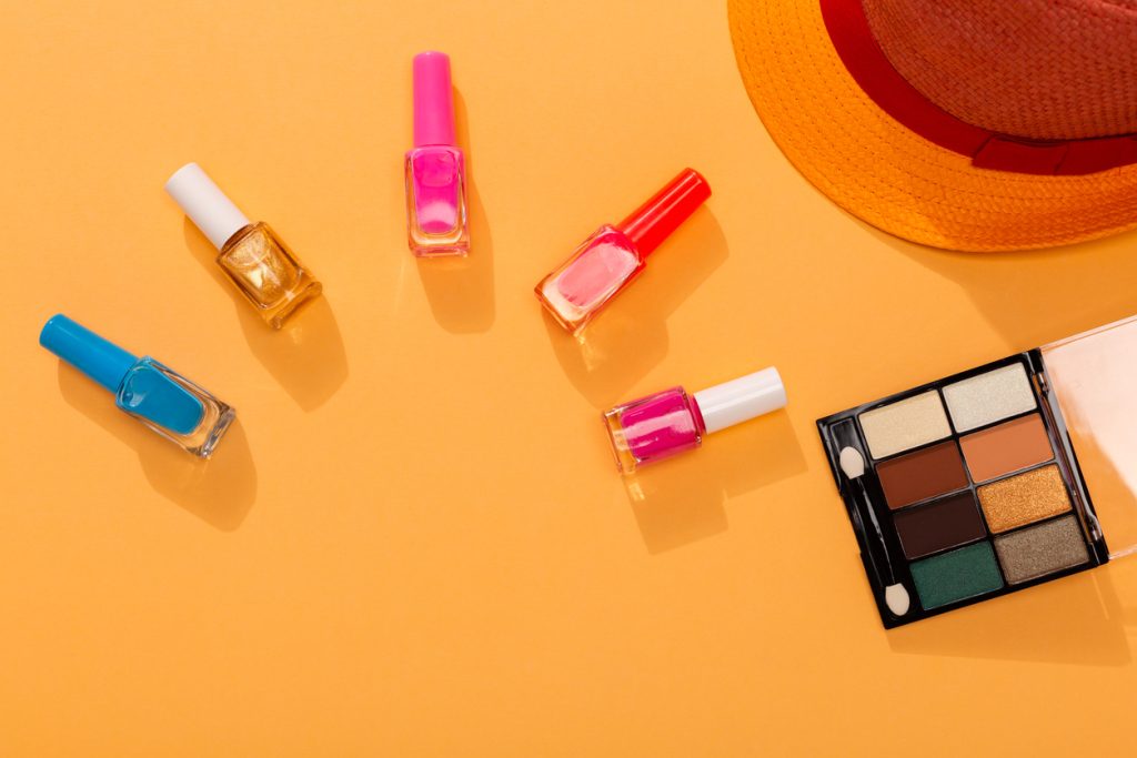 Couleurs vives vernis à ongles variation sur fond orange avec lunettes de soleil et chapeau, comme symbole de la mode estivale.
